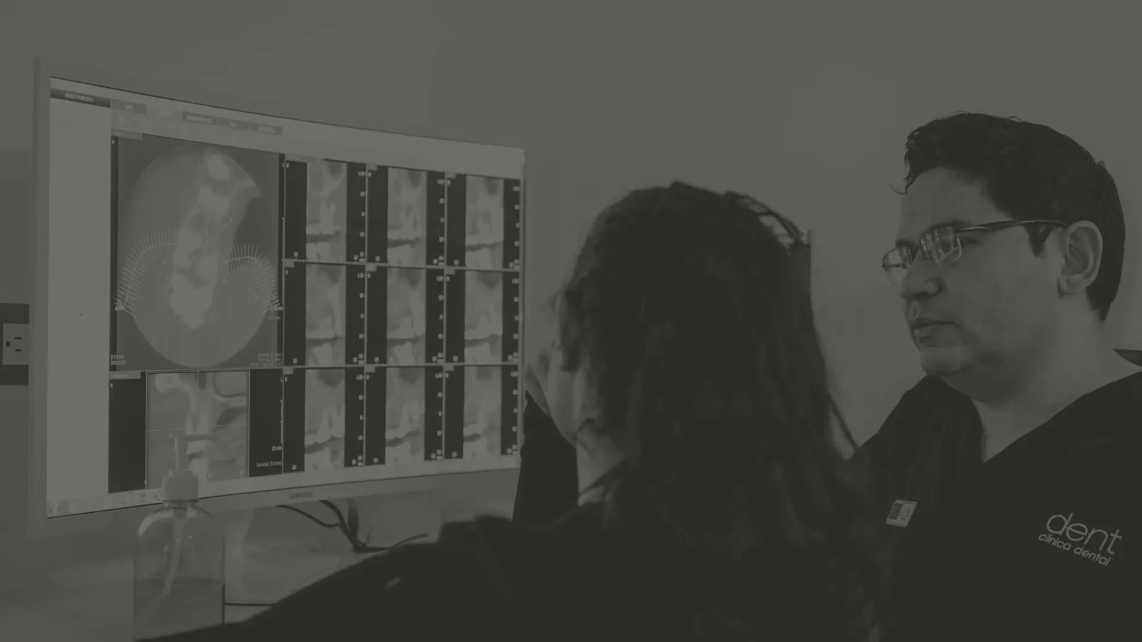 Un especialista de Dent Clínica Dental revisa junto a una paciente un estudio de imagen dental en la pantalla del consultorio