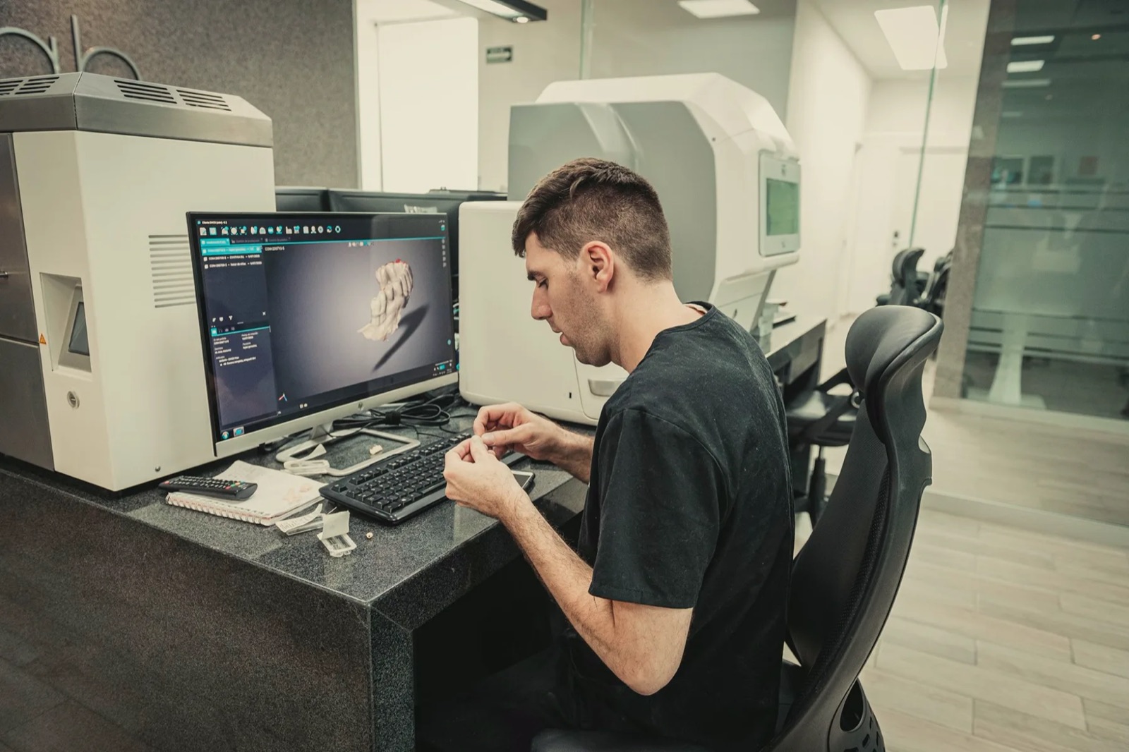 Técnico de Dent Lab diseñando un caso en la estación CAD del laboratorio, junto al equipo de producción