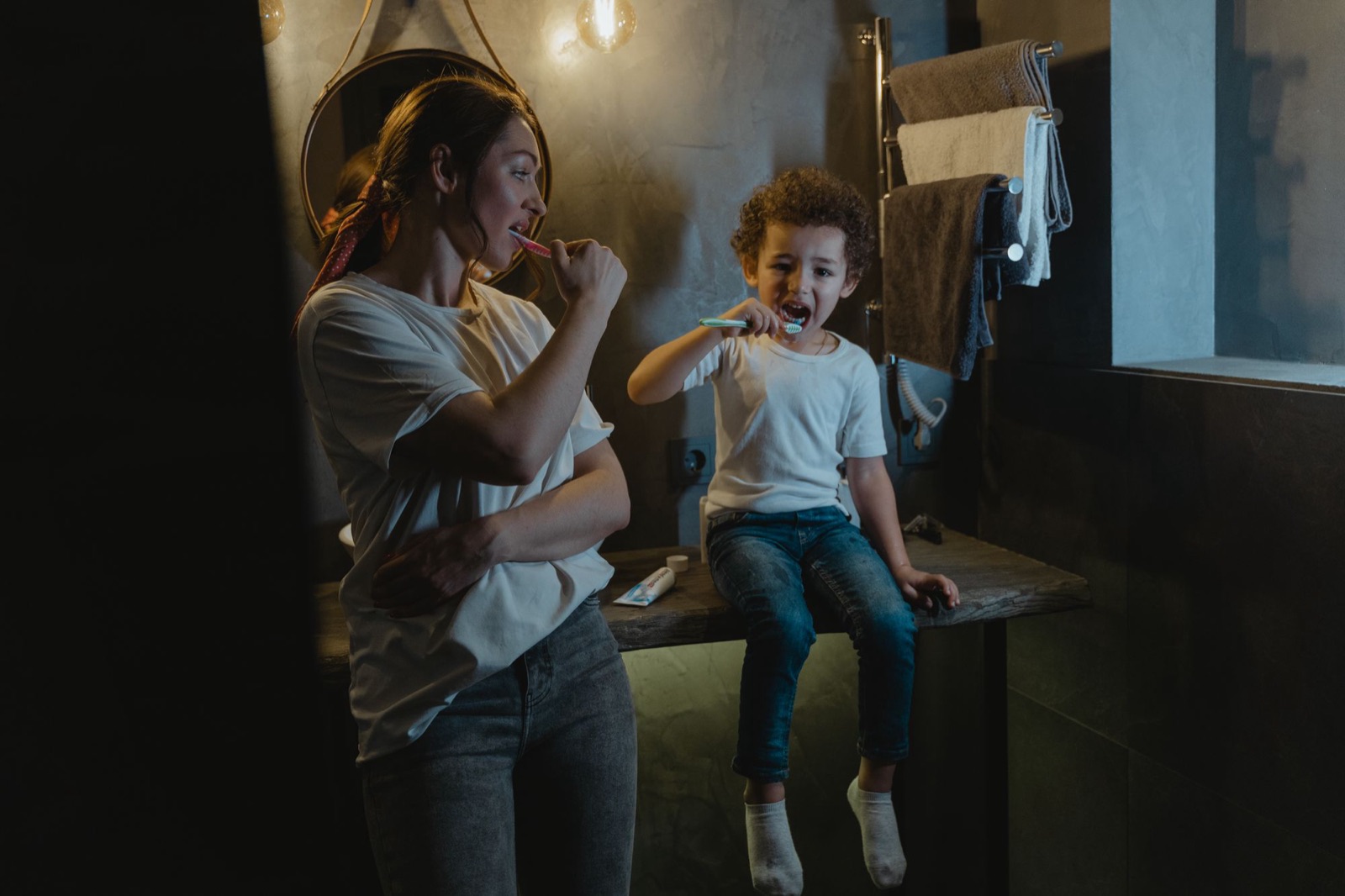 Una mamá y su hijo se cepillan los dientes juntos en el baño de casa
